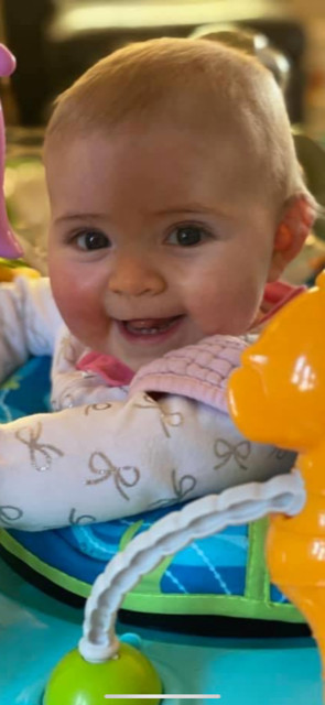 Baby Brynn in a baby walker smiling at camera
