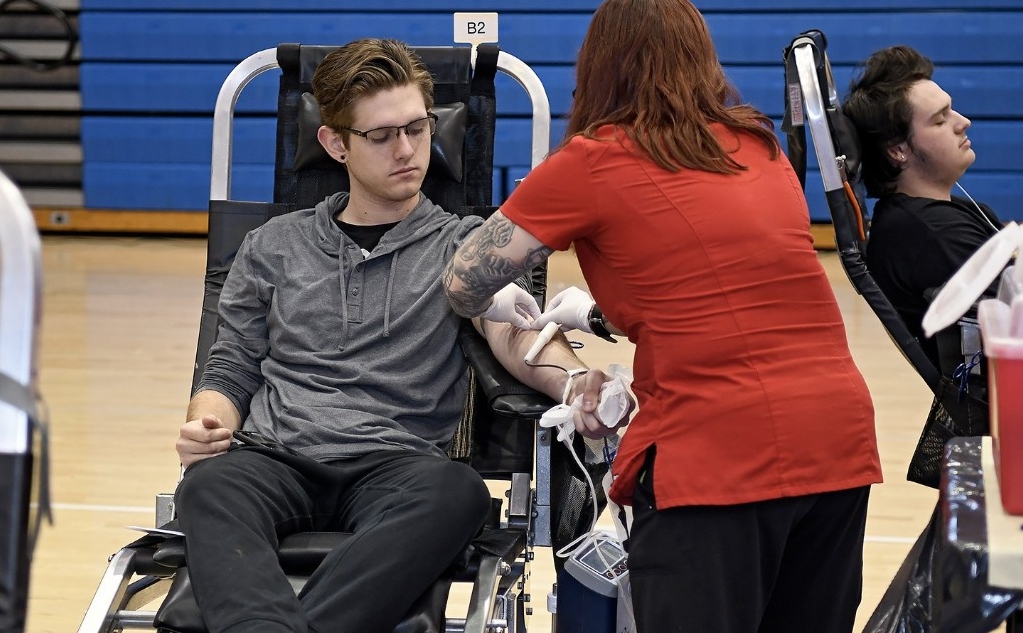 Young male donor giving whole blood at a high school blood drive