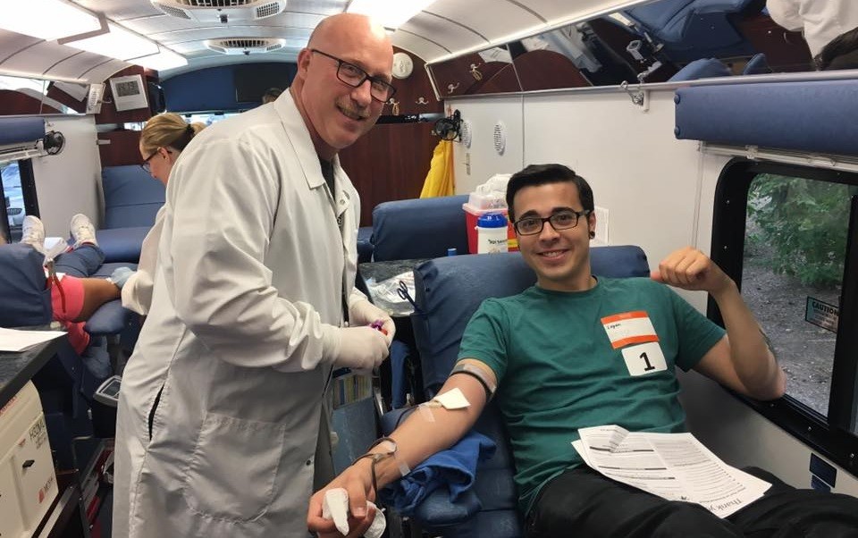 Male donor and Hoxworth phlebotomist in the middle of a whole blood donation on a Hoxworth donor bus