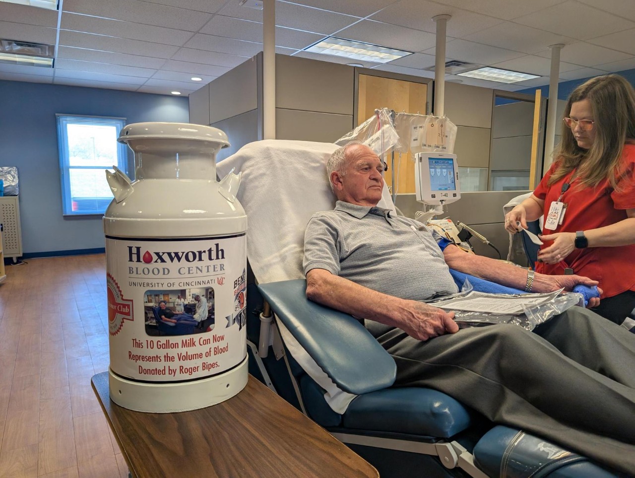 Hoxworth donor Roger Bipes gives blood with his souvenir milk jug