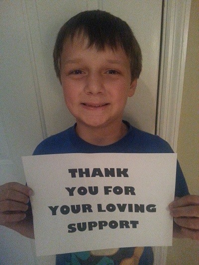 Roman Fariello  holding a sign saying "thank you for your loving support"