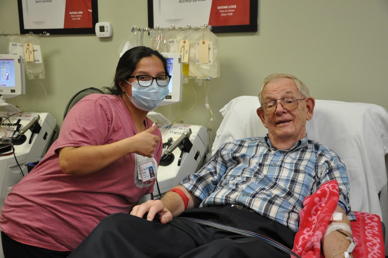 Lauren Coronado wearing a red shirt and face mask, posing next to an older white male platelet donor